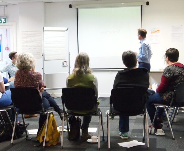 A group of people sitting facing a whiteboard with a man presenting a training course, to illustrate article by Danum Business Solutions