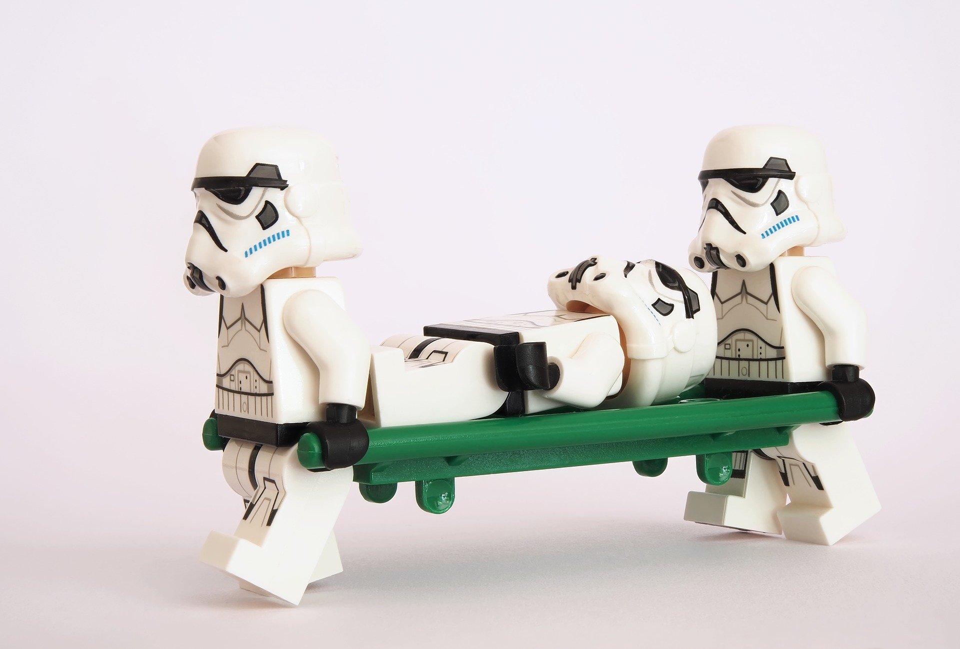 Two Lego Stormtroopers carrying another lego stormtrooper on a stretcher to illustrate first aid at work blog